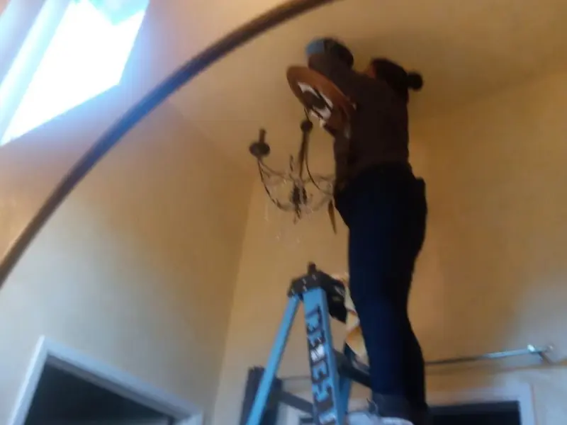 Electrician installing a chandelier in a Cloverdale residence